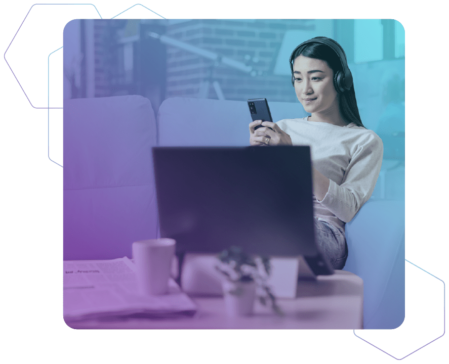 Eine Frau sitzt mit Kopfhörern auf einer Couch und schaut auf ein Smartphone auf rot-blauem Hintergrund, während der Vordergrund einen Schreibtisch und einen Monitor zeigt